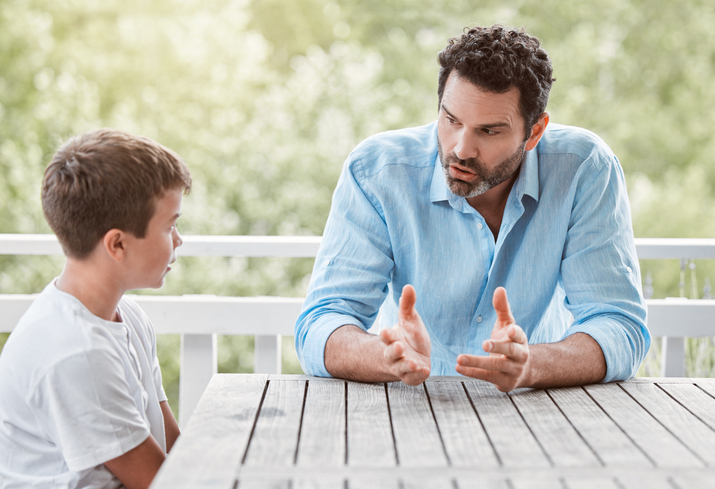 Shot of a young father and son talking outside in the garden at home